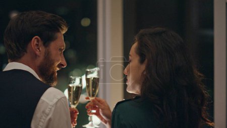 Photo for Happy pair in love drinking champagne together enjoying night city view from window close up. Attractive couple enjoying romantic date late evening. Smiling man relaxing talking with brunette woman. - Royalty Free Image