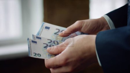 Unknown elegant man counting twenty euros indoors closeup. Bankrupt businessman calculating business income investment profit. Male hands holding cash european currency. Financial loss concept.