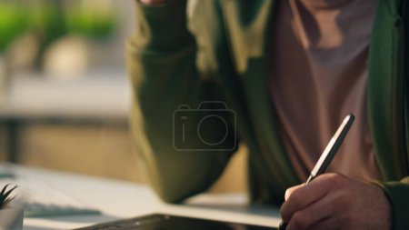 Photo for Artist hand drawing stylus on graphic pad at room close up. Serious web designer talking mobile phone at sunny workplace interior. Focused freelance man creator consulting client watching attentively - Royalty Free Image
