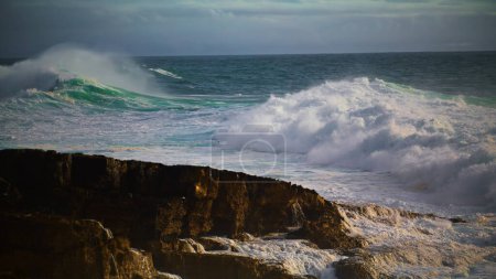 Photo for Huge waves breaking rocky beach in super slow motion. Powerful sea surf rolling towards volcano stones on sunny day. Extreme powerful ocean crashing coastline before storm. Breathtaking cloudy shore - Royalty Free Image
