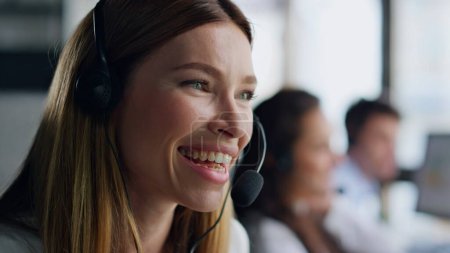 Fröhliche Agenten sprechen Headset Nahaufnahme. Lächelnde Frau im Callcenter. Schöne hilfsbereite Assistentin berät Kunden im Büro aus der Ferne. Positiver Außendienstmitarbeiter bei der Arbeit