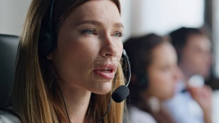 Closeup friendly operator consulting client in headset. Confident woman manager give instructions work data center. Hotline sales specialist talking microphone helping with technical problem on call.