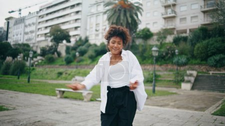 Funky fröhliche Tänzerin genießen Freestyle-Performance auf der Straße der Stadt. Talentierte afrikanisch-amerikanische Künstlerin, die Modern Style Dance aufführt. Lockiger, energischer Performer, der sich rhythmisch in Zeitlupe bewegt.