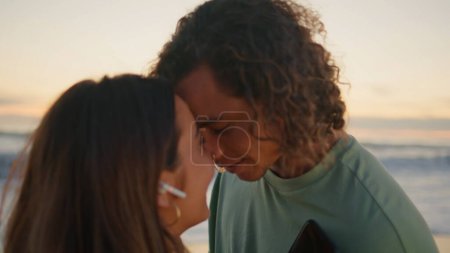 Affectionate couple enjoying music dancing against morning ocean view closeup. Loving man touching foreheads with tender woman at romantic weekend. Smiling earphones lovers relax on sunrise sea nature