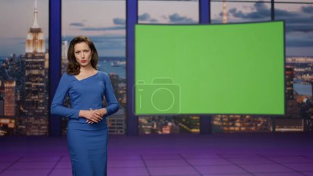 Photo for Gorgeous presenter beginning broadcast breaking news near green screen tv studio. Elegant woman reporter showing information on mockup monitor. Professional anchorwoman lighting daily world events. - Royalty Free Image