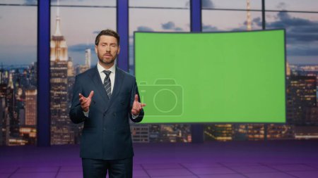 Photo for Presenter showing green screen reporting breaking news in tv channel studio. Bearded newsreader in elegant suit talking about daily events standing at chroma key monitor. Television industry concept. - Royalty Free Image