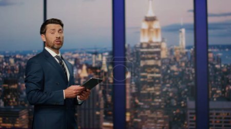 Photo for Professional reporter hosting breaking news at modern television studio stage closeup. Confident bearded presenter speaking at newscast entertainment channel. Serious anchorman lighting current events - Royalty Free Image