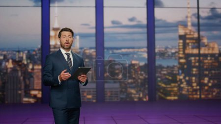 Photo for Man presenter lighting breaking news in modern tv studio standing. Confident newsreader hosting newscast at multimedia channel. Bearded anchorman presenting daily economics politics event in air. - Royalty Free Image