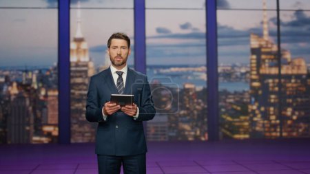 Photo for Anchorman talking breaking news standing stage television studio. Serious man presenter speaking at newscast in tv program. Professional bearded man host lighting important world events. Press concept - Royalty Free Image