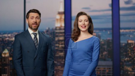 Photo for Positive news readers beginning live tv newscast in modern channel studio close up. Elegant charismatic two presenters smiling talking to audience. Cheerful couple anchors speaking at breaking news. - Royalty Free Image