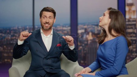 Anchorwoman listening man guest in live tv show studio close up. Happy bearded male expert answering on interview questions from host. Two professional presenters hosting entertainment program in air.