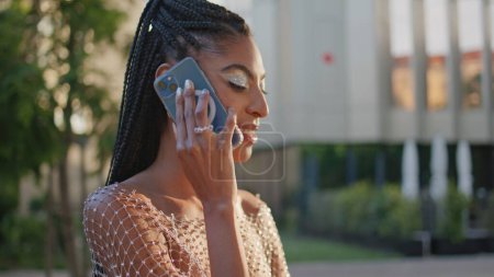 Relajada mujer afroamericana hablando por teléfono móvil en el primer plano de la calle City. Las rastas de moda chica turista terminan llamada telefónica en la plaza de verano. Señora atractiva usando la célula para la comunicación al aire libre