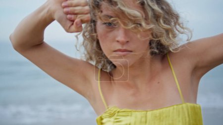 Mesmerizing girl dancing on nature look at camera magnetically close up. Curly blonde dancer moving emotionally closing eyes in dance. Seductive woman performing modern sensual choreography on beach.
