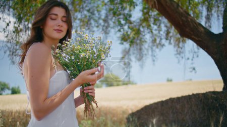 Gentle model sniffing bloom posing at summer nature portrait. Happy carefree woman spreading arms enjoying freedom at rural garden closeup. Relaxed girl strolling windy morning. Summertime concept