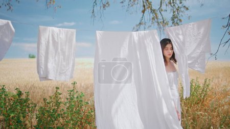 Rural model stepping drying laundry open air place. Tender girl enjoying summer field nature looking camera portrait. Seductive woman posing confidently staring lens at countryside village closeup