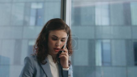 Mujer emprendedora gritando teléfono mirando documentos de trabajo en el lugar de trabajo de cerca. Mujer de negocios irritada argumentando teléfono insatisfecho por informe. Furiosa dama haciendo gestos gritando smartphone en la oficina.