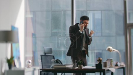 Wütender Unternehmer enttäuscht Anruf werfen Smartphone Gefühl Stress in Luxus-Büro. Genervt beenden bärtige Geschäftsleute das Telefonat, angelehnt an ihren Schreibtisch. Emotionaler Chef vom Scheitern erschöpft.