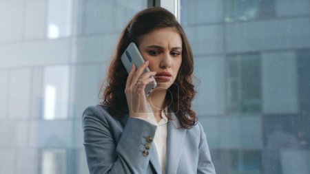 Genervte Geschäftsfrau ruft am modernen Firmenarbeitsplatz aus nächster Nähe an. Verwirrte Managerin schaut auf Geschäftspapiere am Schreibtisch und telefoniert nervös. Wütendes Mädchen unzufrieden mit Telefonat.