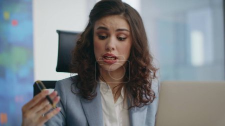 Nervous businesswoman complaining at online meeting sitting company office closeup. Displeased lady boss quarrelling at video call looking laptop on modern workplace. Emotional girl manager in despair