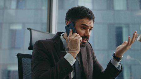 Unzufriedene Regisseure, die in handybesorgten Arbeitsergebnissen argumentieren, nähern sich an. Wütender bärtiger Geschäftsmann schreit im Büro mit Smartphone. Genervter nervöser Ceo-Manager streitet sich am Telefon über Ärger.