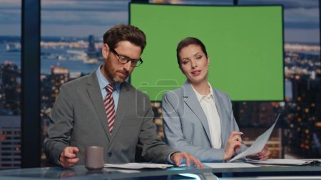Mockup tv studio presenters broadcasting news in air multimedia channel closeup. Elegant couple anchors showing daily events on green screen monitor. Smiling newsreaders live reporting together