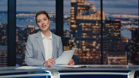 Photo for Friendly newsreader speaking newscast evening television studio closeup. Confident woman host lighting world political situation sitting newsroom desk at light. Professional tv broadcasting concept - Royalty Free Image