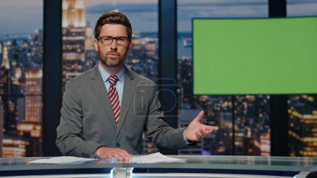Photo for Serious anchor delivering news standing modern studio. Confident bearded man host saying goodbye to viewers ending evening newscast. Professional television presenter working world events programme - Royalty Free Image