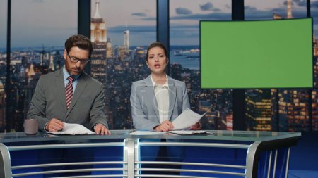 Photo for Newscasters broadcasting green screen news at late studio closeup. Friendly anchors couple working on chroma key tv talking to viewers. Elegant smiling presenters speaking at evening newscast together - Royalty Free Image
