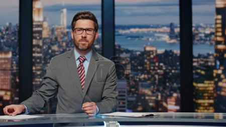 Photo for Anchorman reporting tv live news evening program. Professional male presenter talking at television cable channel. Smiling bearded broadcaster speaking in newsroom studio delivering latest stories - Royalty Free Image