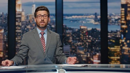 Photo for News presenter broadcasting studio. Positive bearded anchor man gesturing hand bringing up important day events. Authority announcer sharing latest evening updates delivering information at work - Royalty Free Image
