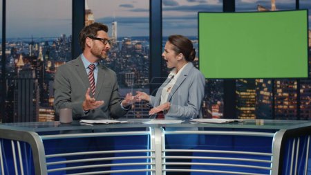 Couple anchors discussing mockup news at evening stage tv studio closeup. Friendly presenters communicating together joking on modern channel. Positive two newsreaders talking to audience smiling