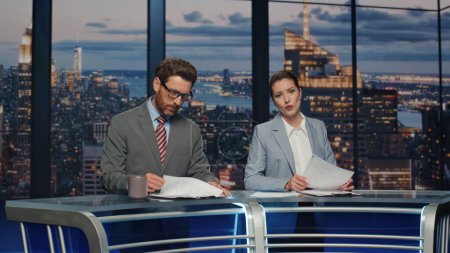 Photo for Professional television presenters talk evening newscast at modern studio closeup. Confident anchors announcing news broadcasting in newsroom together. Elegant couple hosts lighting daily world events - Royalty Free Image