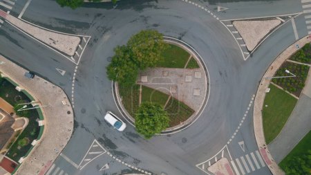 Grüner Kreisverkehr von oben in einer kleinen europäischen Stadt. Autos auf Asphalt Kreuzung mit kreisförmiger Bewegung. Moderne Transportfahrzeug-Infrastruktur aus der Luft. Autos überqueren Kreisverkehr