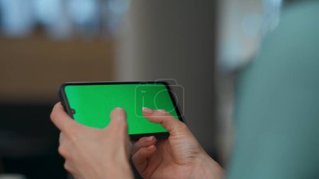 Photo for Director arms playing mockup smartphone game indoors. Closeup anonymous executive resting with green screen cellphone touchpad at office. Woman hands typing enjoying horizontal chroma key mobile - Royalty Free Image