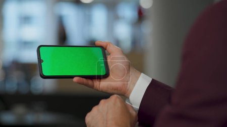 Photo for Closeup hands using green screen smartphone at lounge. Formal wear man touching modern mockup phone. Unrecognized company owner working on chromakey device. Business analyst checking information - Royalty Free Image
