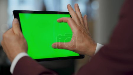 Photo for Closeup man hands swiping green tablet screen in luxury office. Unrecognized professional ceo using chroma key digital pad checking presentation. Finance analyst browsing web market at mockup device - Royalty Free Image