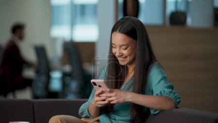 Gadget user laughing reading jokes at office lounge closeup. Millennial entrepreneur watching funny news online using smartphone. Ceo woman resting at open space workplace. People emotions concept 