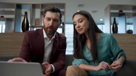 Multiracial colleagues discussing presentation at office. Business team talking analyzing project on laptop. Man and woman working together. Businessman pointing finger on screen. Partnership concept