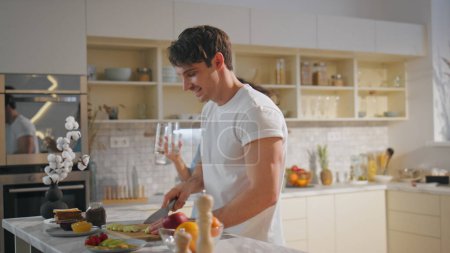 Couple enjoy family breakfast cooking together on cozy kitchen. Happy loving wife helping prepare food to handsome young husband. Affectionate spouses talking laughing at romantic weekend in home.