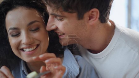 Loving couple eating apple slices at kitchen enjoying love tenderness close up. Portrait of affectionate spouses laughing hugging on family breakfast. Beautiful young woman cutting fruit feeding man.