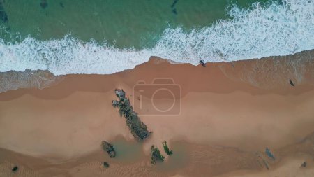 Téléchargez les photos : Vagues moussantes lavant la plage en vue aérienne. Textures turquoise sculptant l'océan dans le sable. Océan calme contrastant avec vue dynamique sur la côte. Drone de la frontière ondulée pacifique entre terre et mer. - en image libre de droit