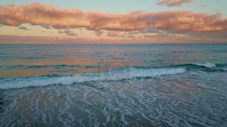 Aerial twilight ocean view. Golden hour bring vibrant colors to waves and surf. Evening painting sky vast sea with warm palette at sunset. Tranquil waters reflecting peaceful glow along shoreline.