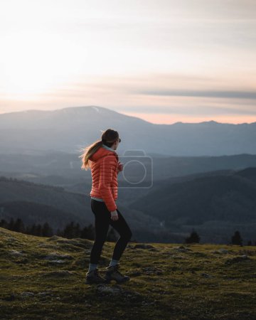 Photo for Girl with warm clothes walks through the Urkiola mountain in a sunset of warm lights but very cold - Royalty Free Image