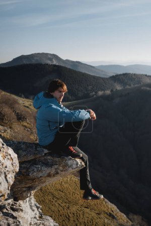 Téléchargez les photos : Garçon regardant l'horizon assis sur un rocher au coucher du soleil dans les montagnes de duranguesado à Vizcaya, Pays Basque - en image libre de droit