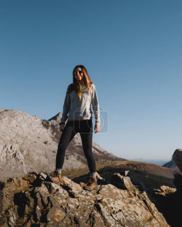 Foto de Niña alta con el pelo largo sonriendo de pie sobre una roca en las montañas de Urkiola cerca de Anboto en vizcaya - Imagen libre de derechos