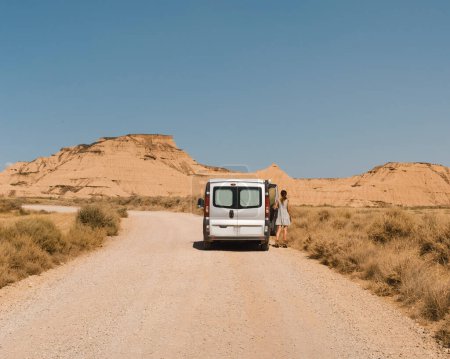 Téléchargez les photos : Fille d'un van sur un chemin de terre dans le désert lors d'un voyage à travers les Bardenas Reales de Navarre, Espagne. - en image libre de droit