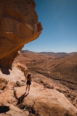 Téléchargez les photos : Fille dans un paysage désertique des montagnes de Fuerteventura dans les îles Canaries - en image libre de droit