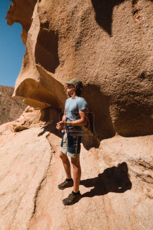 Téléchargez les photos : Homme debout dans le paysage rocheux du désert de fuerteventura lors d'un trek - en image libre de droit