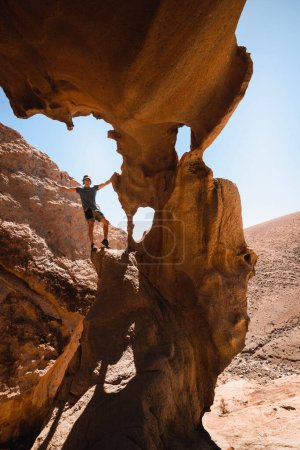 Téléchargez les photos : Heureux homme dans les formations rocheuses spectaculaires d'un canyon de grès désertique à Fuerteventura - en image libre de droit