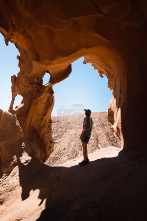 Téléchargez les photos : Homme observant les formations rocheuses d'un canyon désertique de grès à Fuerteventura - en image libre de droit